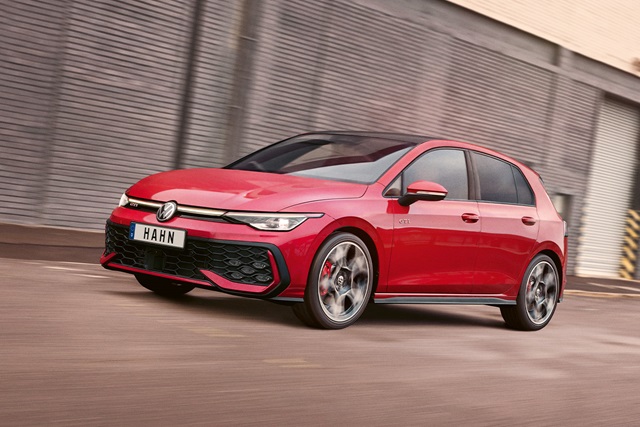 Roter VW Golf GTI fährt seitlich vor einer grauen Metallwand mit dem Kennzeichen 'HAHN'