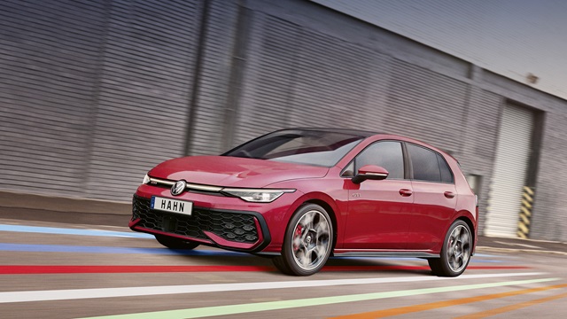 Roter VW Golf GTI fährt seitlich vor einer grauen Wand mit bunten Linien auf dem Boden