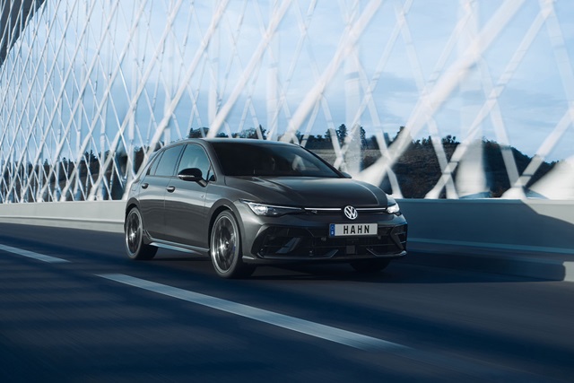 Grauer VW Golf R-Line fährt auf einer modernen Brücke mit Stahlseilgeländer