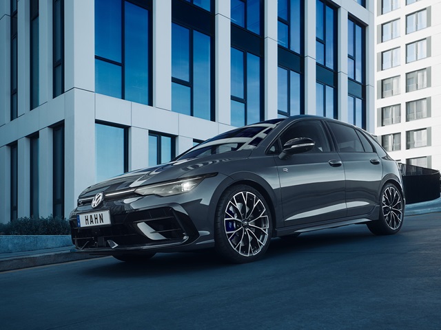 Seitliche Ansicht eines grauen VW Golf R-Line mit sportlichen Felgen vor einem modernen Bürogebäude