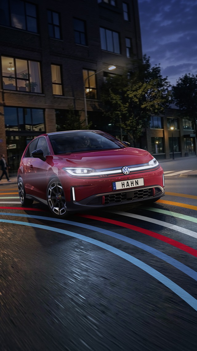 VW ID. Polo GTI in roter Lackierung mit LED-Scheinwerfern und markanten Felgen in Frontansicht auf einer Straße mit bunten Linien, Kennzeichen 'HAHN'