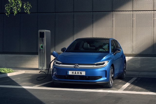 Blauer VW ID. Polo steht an einer Ladestation vor einer modernen, dunkelgrauen Wand
