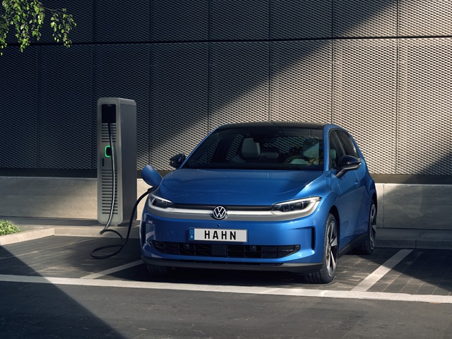 Blauer VW ID. Polo steht an einer Ladestation vor einer modernen, dunkelgrauen Wand