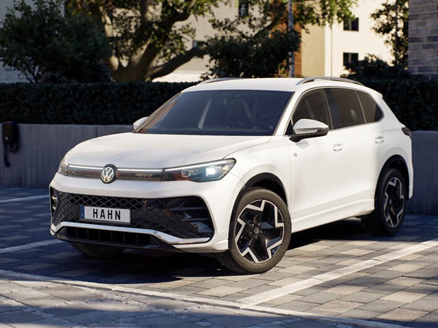 Weißer VW Tiguan R-Line mit schwarzem Kühlergrill und markanten Felgen in Frontansicht auf gepflastertem Platz
