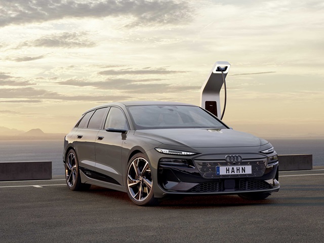 Audi A6 e-tron vor einer Ladestation bei Sonnenuntergang.