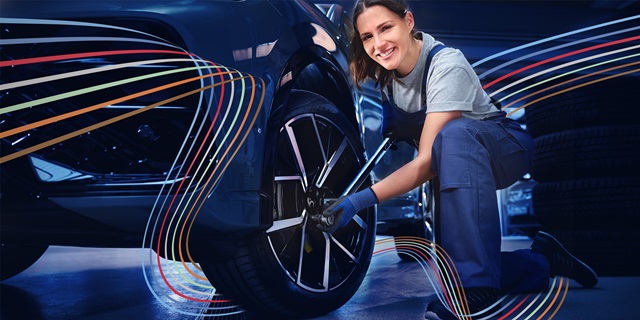 Eine Mechanikerin wechselt Räder.